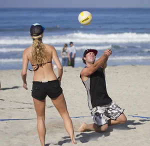 Hot girls playing beach volleyball in bikinis and shorts