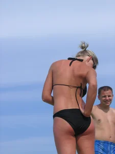 Cute blonde on the beach in a black bikini with nice boobs