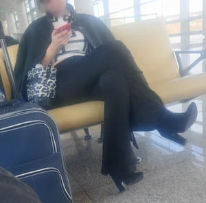 Girl in Pants And High-Heeled Shoes Sitting at the Station With Crossed Legs