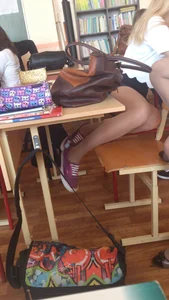 Teen Blonde in a Blouse, Skirt And Pantyhose Sitting in Class With Bent Legs