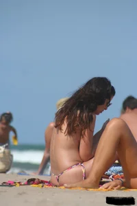 2 topless girls at the beach in thongs