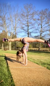 Non-candid gymnast teen showing off her stretch while wearing rollerblades and a leotard in the park