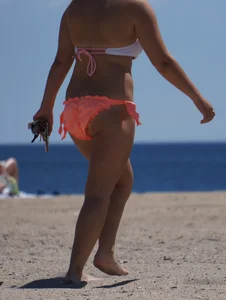 Thick blonde girl in an orange bikini on the beach