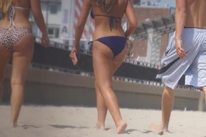 Two sexy friends, one blonde and one brunette, on the beach in bikinis