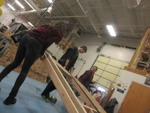 Candid Girl in Skinny Jeans Helping Carry Something at a Workshop
