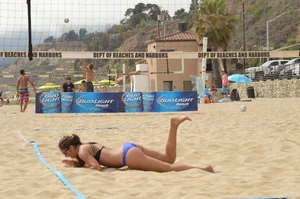 Sexy beach volleyball girl in sport bra top with pokies and blue bikini bottom