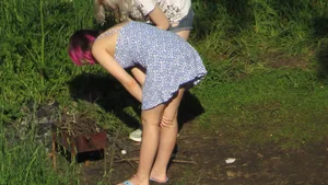 Cute Girl in a Dress Bending Over BBQ Grill in the Countryside Creepshots