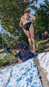 A pretty brown haired woman bending over with her nice ass in a black bikini on the beach. oc