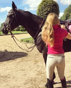 Girl checking a saddle wearing tight beige jodhpurs