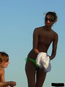 Topless girl on the beach with small boobs wearing a green thong bikini