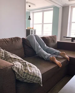 Barefoot Girl in Pants Hanging Over the Back of the Sofa
