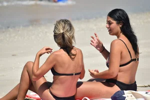 Blonde and brunette on the beach looking sexy in their bikinis