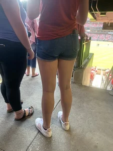 Bunch of girls in various outfits at a Cardinals baseball game
