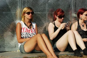 Three girls sitting, one redhead in jeans and a redhead and blonde in shorts