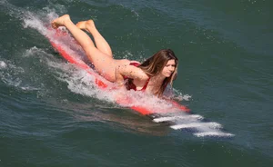 Hot surfer girl in a one-piece swimsuit in water