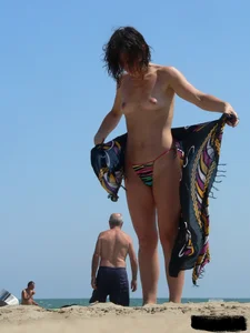 Topless beach milf looking sexy in a tiny g-string bikini