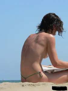 Topless beach milf looking sexy in a tiny g-string bikini
