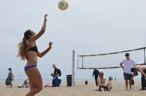 Sexy beach volleyball girl in sport bra top with pokies and blue bikini bottom