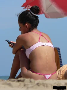 Hot brunette ethnic girl on the beach in a pink thong bikini