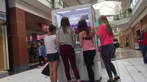 Little blonde teen in grey leggings at the mall with her friends
