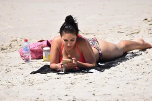 Huge boobed thick brunette babe on the beach in a bikini