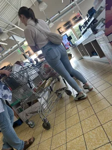 Tight cheek hugging jeans on brunette in line at shop