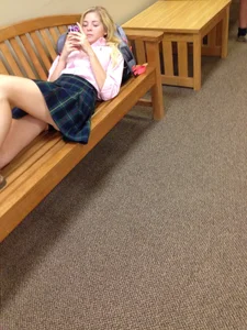 Blonde girl in a skirt lying on a bench