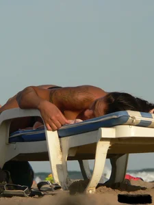 Topless tattooed lady on the beach with fake big tits