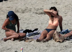 Big boobed babe with pokies in a bikini on the beach with friends