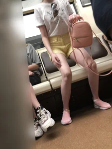 Skinny Girl in Pink Sneakers and Yellow Shorts Standing Up in a Subway Train