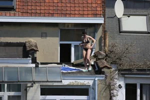 Neighbor on rooftop tanning in bikinis