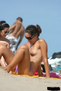 2 topless girls at the beach in thongs