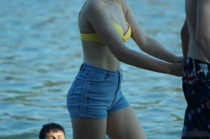 Hot Girl in Swimsuit Top and Denim Shorts by the Water on the Beach Creepshots