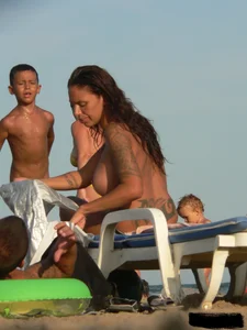 Topless tattooed lady on the beach with fake big tits