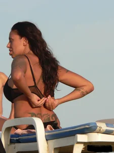 Topless tattooed lady on the beach with fake big tits