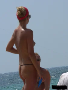 Topless skinny blonde lady in a g-string bikini at the beach