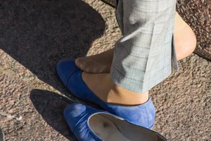 Feet in transparent short socks and flats closeups on the street: candid girl taking off her shoe and plating with her foot in public