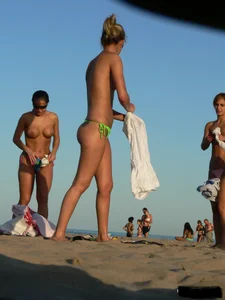 Topless girl on the beach with small boobs wearing a green thong bikini