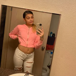 Girl in Torn Jeans and a Pink Top With a Plump Tummy Mirror Selfie