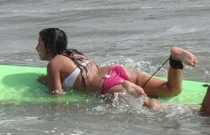 Brunette bikini girl on the beach and surfing in her bikini
