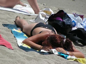 Sexy girl in black bikini dressing on the beach