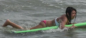Brunette bikini girl on the beach and surfing in her bikini