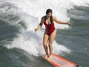 Hot surfer girl in a one-piece swimsuit in water