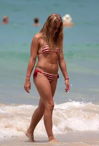 Blonde looking sexy on the beach in red striped bikini