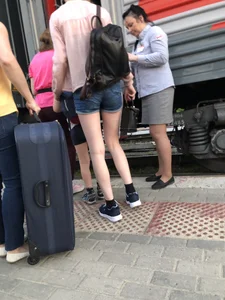 Candid with long thin legs wearing denim shorts waiting to get on a train
