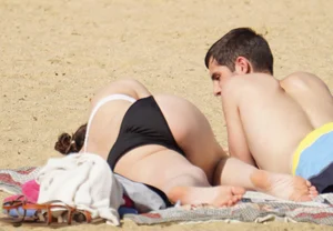 Sexy girl on the beach laying out and bending over in her bikini