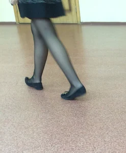 College candid teen's closeup as she's walking in a hallway - a skirt, black pantyhose and flats