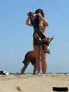 Topless beach milf looking sexy in a tiny g-string bikini