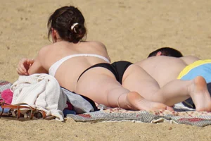 Sexy girl on the beach laying out and bending over in her bikini