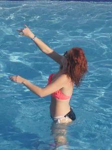 Sexy red haired girl in pink and black bikini at the pool